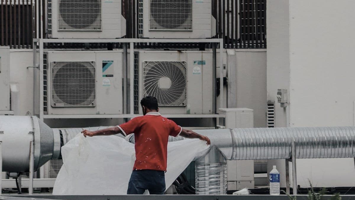 An HVAC technician working on rooftop AC units